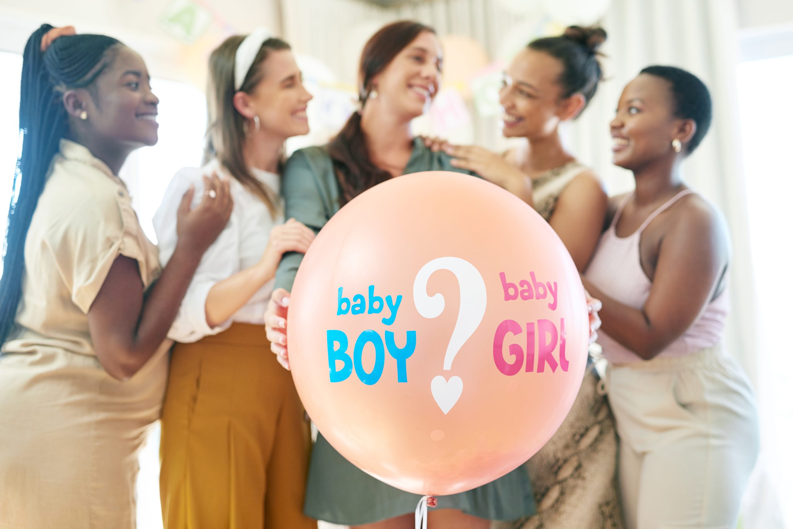 Shot of a group of women about to pop a balloon for a gender reveal during a baby shower.