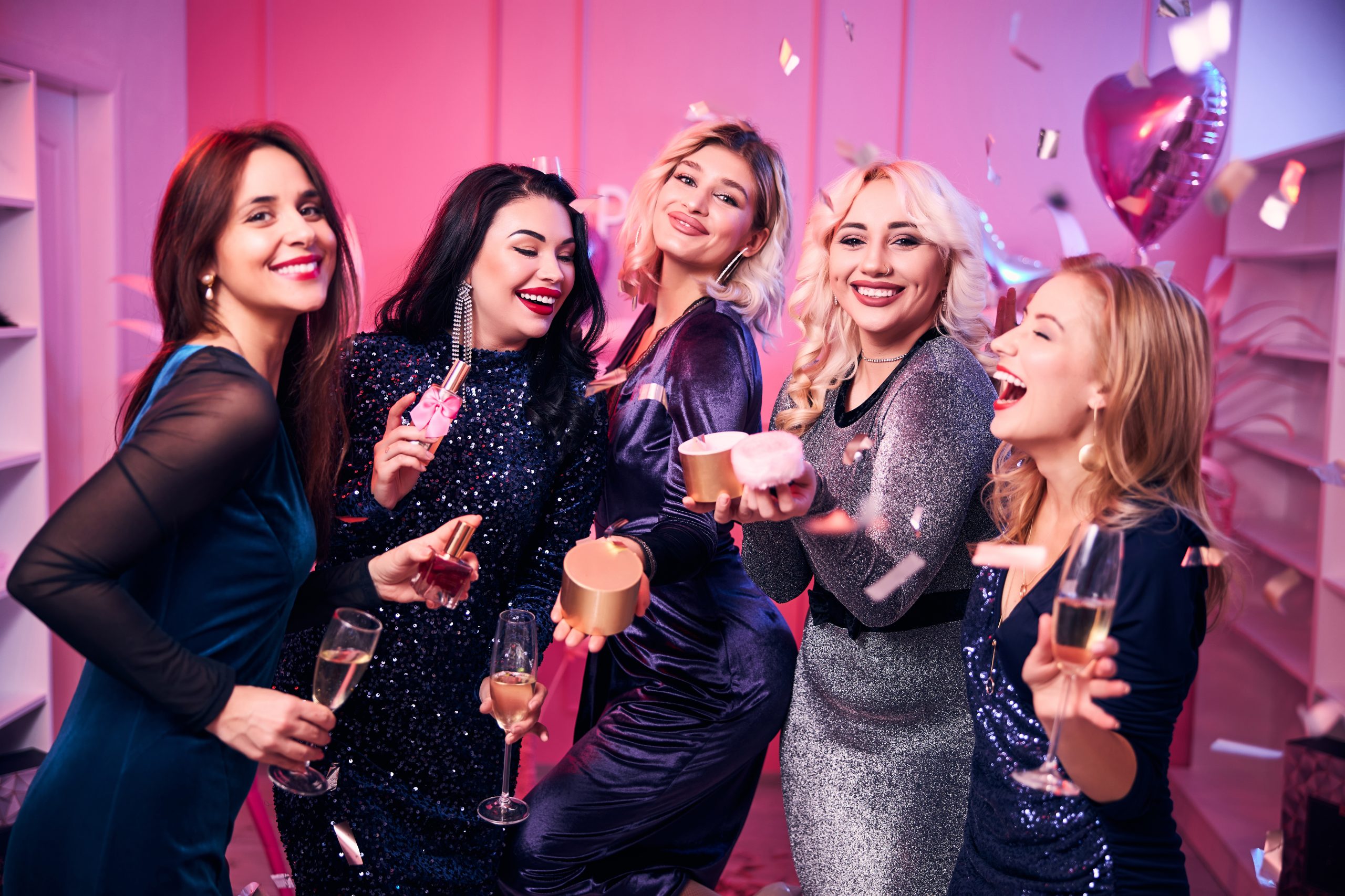 Good-looking joyful coworkers with gifts and champagne flutes in their hands posing for the camera